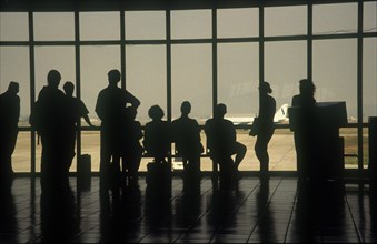 VIETNAM, Hanoi, People at the airport terminal viewed from behind silhouetted against the window.