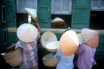 VIETNAM, Hue, "Traditional conical, straw hats being sold to train passengers at Hue station."