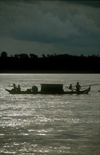 CAMBODIA, Stung Treng, "Narrow barge on the Mekong River, oarsmen silhouetted against sparkling