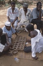 TANZANIA, Zanzibar Island, People, Group of young men playing traditional board game.