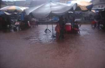 CAMBODIA, Kratie, "People sheltering under large umbrellas during monsoon floods, water covering