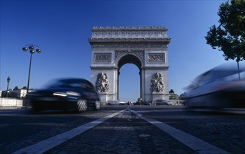 FRANCE, Ile de France, Paris, The Arc de Triomphe with cars speeding away from it