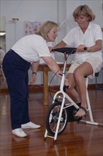 20010198 SPORT Injuries Physiotherapist  Female sport physiotherapist with female patient on exercise bike