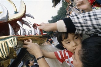 JAPAN, Festival, Young boy held up by his mother to touch the face of the dragon during a dragon