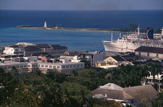 BAHAMAS, Nassau, View over houses to harbour with a cruise ship at dockside and a lighthouse in the