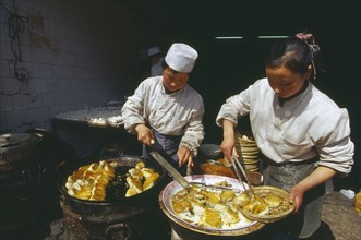 CHINA, Shaanxi Province, Xian, Two cooks preparing dish of fried food.