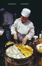 CHINA, Shaanxi Province, Xian, Cook turning food frying in large pan in front of him.