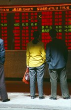 CHINA, Shaanxi Province, Xian, People reading stocks and shares financial information displayed in