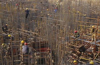 CHINA, Shaanxi Province, Xian, Construction workers on scaffolding amongst steel fixing on a
