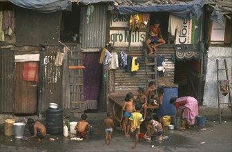 INDIA, Maharashtra, Mumbai , Slum housing with group of children washing in buckets outside.