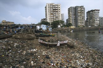 INDIA, Maharashtra, Mumbai , Polluted shoreline covered with rubbish with shanty housing and