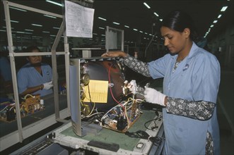 INDIA, Karnataka, Bangalore, Woman in factory making electrical components for televisions.