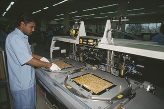 INDIA, Karnataka, Bangalore, Man working in a factory producing circuit boards.