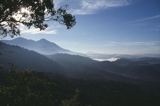 INDIA, Kerala, Western Ghats, View near Munnar over tree covered hills in drifts of mist.