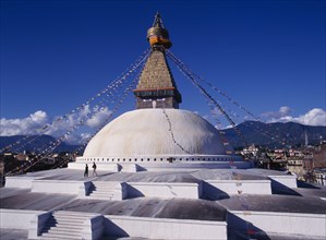 NEPAL, Kathmandu, Bodhnath stupa hung with prayer flags with visitors on surrounding steps.
