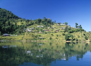 NEPAL, Annapurna Region, Pokhara, View over Lake Phewa with reflected terrace hillside and trees.