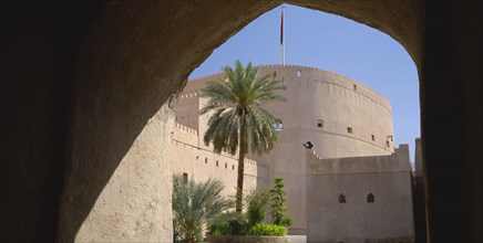 OMAN, Nizwa, "Nizwa Fort, built in the mid seventeenth century.  Exterior view framed by archway in