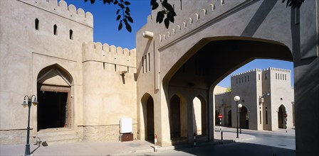 OMAN, Nizwa, Town centre with crenellated walls and archway over empty street.