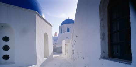 GREECE, Cyclades Islands, Santorini, "Part view of white painted church with blue, domed roof."