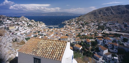 GREECE, Saronic Islands, Hydra, View over tiled rooftops of Hydra Town to harbour and distant
