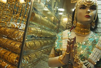 UAE, Dubai, The Gold Souk.  Shop window display with mannequin draped in gold jewellery beside