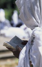 ETHIOPIA, Addis Ababa, "Woman in white head covering reading from book during ceremony at St George