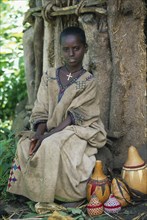 ETHIOPIA, Harerge Province, General, Young girl sitting in front of tree trunk with decorated