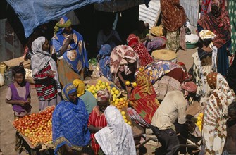 ETHIOPIA, Harerge Province, Jijiga, Market.  Women in brightly coloured dress at fruit stall.
