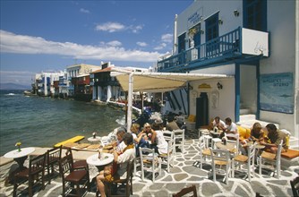 GREECE, Cyclades Islands, Mykonos, People at waterside cafe with gallery above.