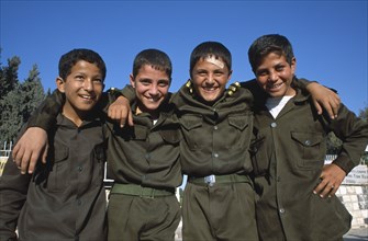 SYRIA, Central, Hama, "Four smiling schoolboys in uniform, standing in a line with their arms