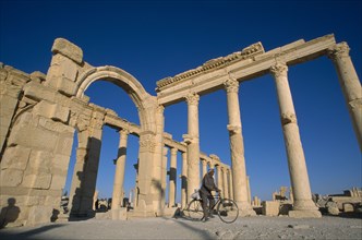 SYRIA, Central, Tadmur, Colonnade and archway with man on a bicycle framed between columns.