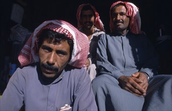 SYRIA, Central, Tadmur, "Two seated men wearing traditional red and white checked headscarves,