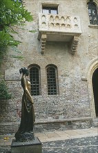ITALY, Veneto, Verona, Juliet’s balcony or Casa di Giulietta with statue of Juliet in the courtyard