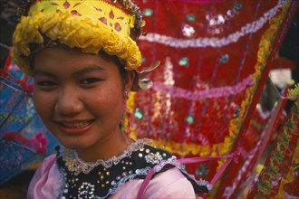 THAILAND, Chiang Mai, "Girl dancer at hill tribe event in yellow, pink and red costume.  Head and