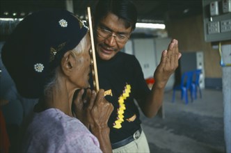 THAILAND, Tak Province, Mae Sot, Male optician giving an elderly woman an eye test at the Mae Tao
