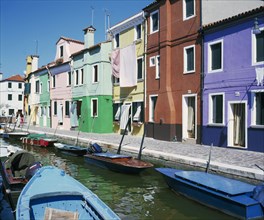 ITALY, Veneto, Venice, Burano Island.  Tenders moored in canal outside row of brightly painted