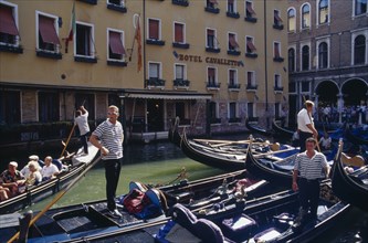 ITALY, Veneto, Venice, "Gondolas tied up at Hotel Cavalletto, with gondolier and tourist passengers