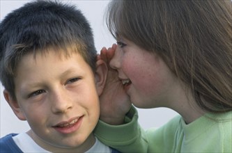 HEALTH, Hearing, Young girl whispering into the ear of a boy.