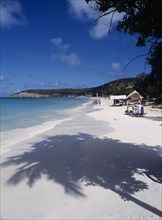 WEST INDIES, Antigua, Dickenson Bay, View along quiet sandy beach towards sunbathers and beach