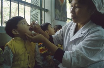 VIETNAM, North, Hanoi, Primary school children receiving oral polio immunization from nurse.