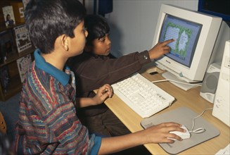 BANGLADESH, Dhaka, Two young boys learning English through computer games.