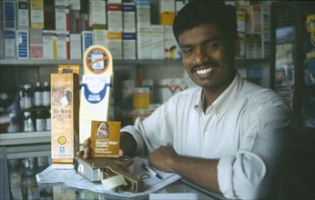 INDIA, Tamil Nadu, Madras, Male chemist displaying condoms.