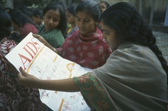 INDIA, West Bengal, Calcutta, Women reading Aids awareness poster.