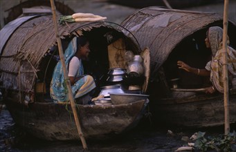 20017896 BANGLADESH  Transport Two female river gypsies in covered wooden boats talking to each other.