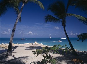 WEST INDIES, Antigua, Dickenson Bay, "Sandy beach and rocks with sunbather on lounger.  Aquamarine