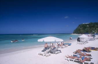 WEST INDIES, Antigua, Long Bay, Beach overlooking semicircular bay with sunbathers on white sun