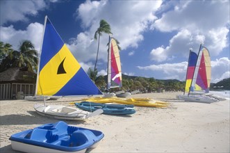 WEST INDIES, Antigua, Jolly Beach, Line of boats with brightly coloured sails pulled up onto empty
