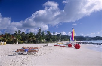 WEST INDIES, Antigua, Jolly Beach, Sandy beach fringed with palm trees with sailing boat and