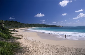WEST INDIES, Antigua, Half Moon Bay, View over sandy beach and semicircular bay with woman walking