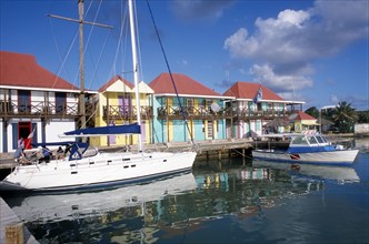 WEST INDIES, Antigua, St Johns, Redcliffe Quay.  Boats moored beside wooden jetty with colourful